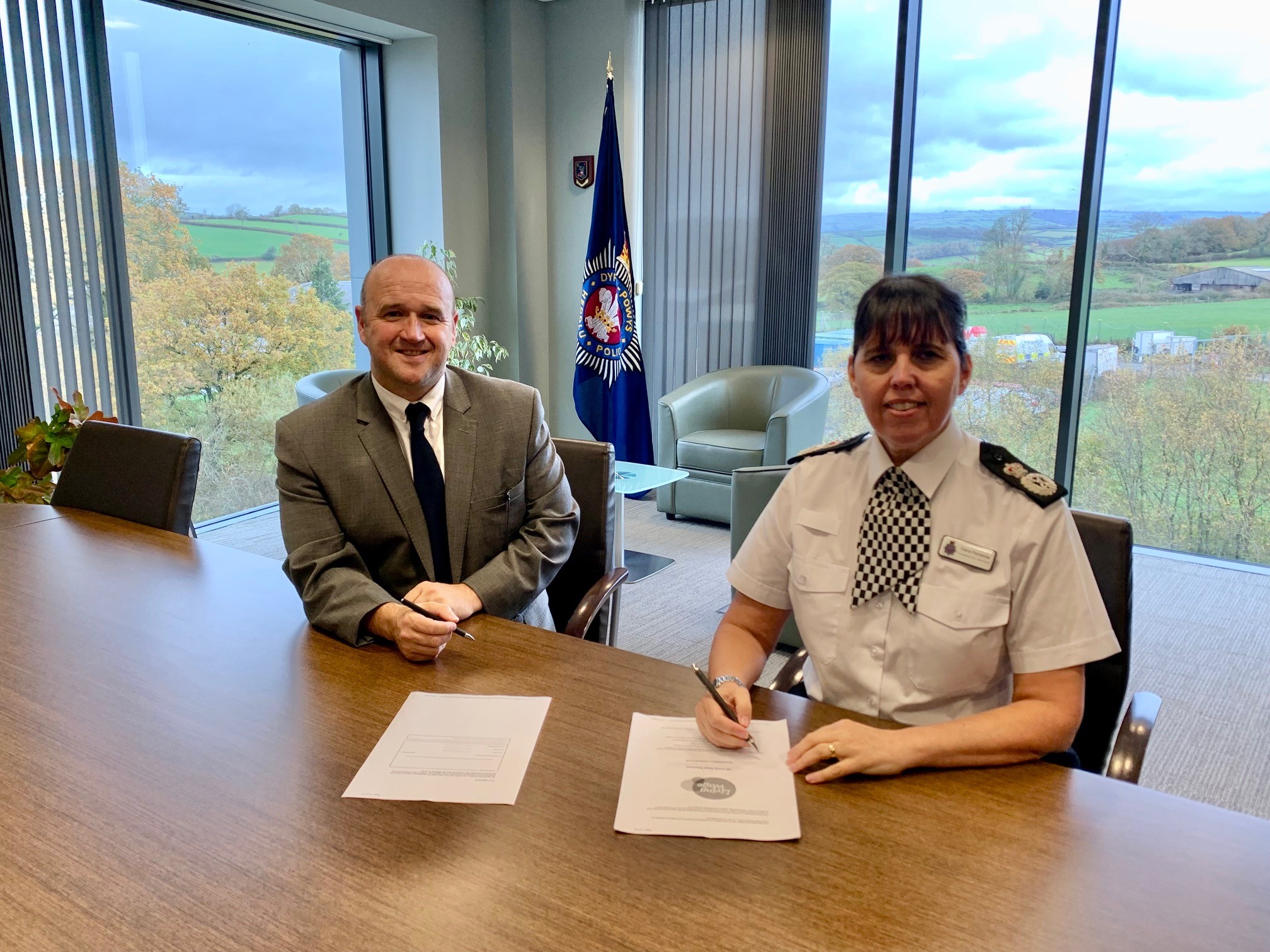 Police and Crime Commissioner Dafydd Llywelyn and Temporary Chief Constable Claire Parmenter signing the Dyfed-Powys Police commitment agreement to become a Living Wage Employer.